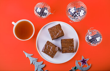 Dark chocolate brownie cakes in a plate on a red background for Christmas holidays