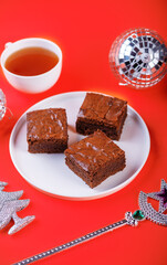 Dark chocolate brownie cakes in a plate on a red background for Christmas holidays