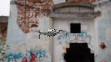 A drone in the sky next to a ruined, abandoned building