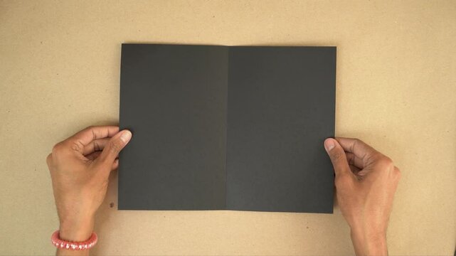 Folding letter-sized black cardstock for card-making or scrapbook project, overhead view
