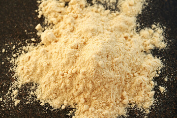 A heap of whey protein powder on dark background
