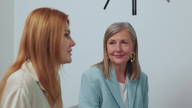 Footage of mother and daughter sitting at beautician's appointment, talking. Smiling ute elegant woman looking at adult daughter and listening attentively. Indoors. Healthcare concept