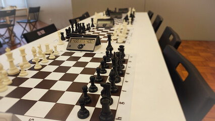 An empty hall with tables on which chess boards and timers are prepared. Concept of competition sport chess, leadership skills, self-development.