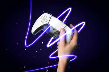Woman holding video game controller on dark blue gradient background, closeup. Glowing neon string of light around hand with device