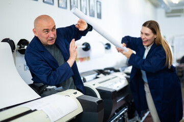 Fototapeta premium Positive printing office workers in uniform fighting with rolled paper during break just for fun.