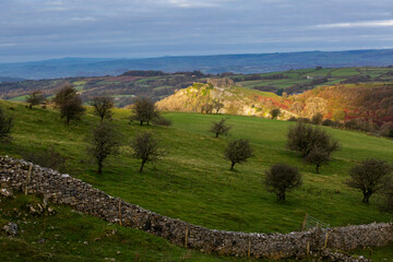Naklejka premium Carreg Cennen castle sitting high on a hill basking in morning sunlight in Carmarthenshire, South Wales UK 