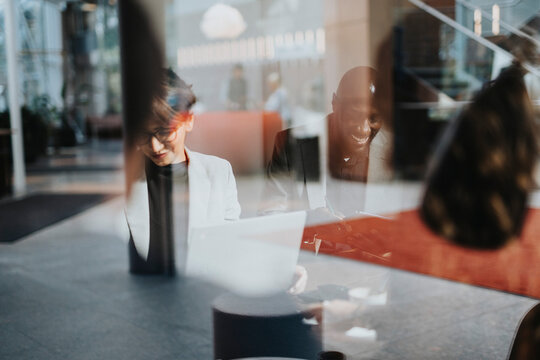 Smiling bald businessman working with female colleague seen through glass