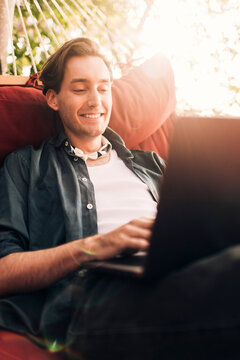 Smiling young man using laptop while sitting in hammock