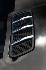 Close-up of chrome-plated air intakes on the hood of a black car