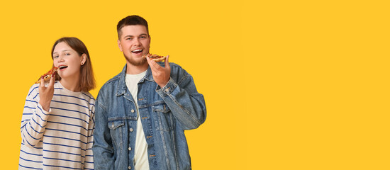 Beautiful young happy couple with pieces of tasty pizza on yellow background