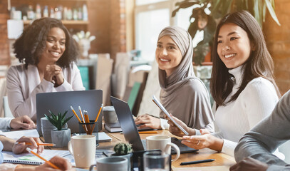 Close up of young cheerful international team having business meeting in modern office