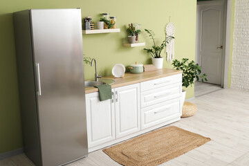 Interior of kitchen with silver fridge, counters and shelves
