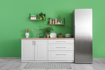 Interior of kitchen with silver fridge, counters and shelves