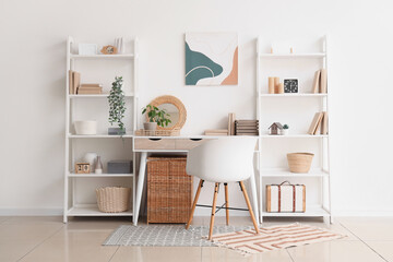 Interior of stylish modern room with workplace and shelving units near white wall