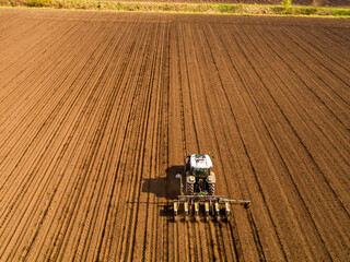 Tractor seeding crops in plowed field aerial view