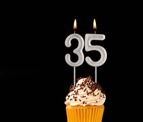 Number 35 shaped candles - Birthday cupcake on black background.