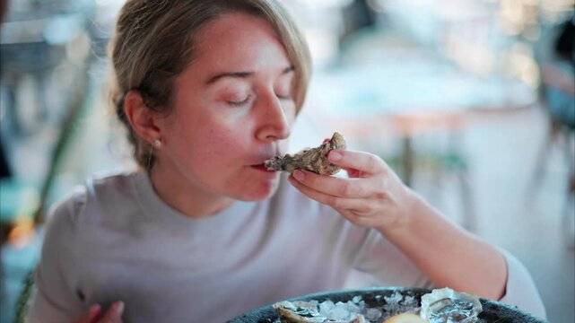 Woman eating raw oyster at a restaurant