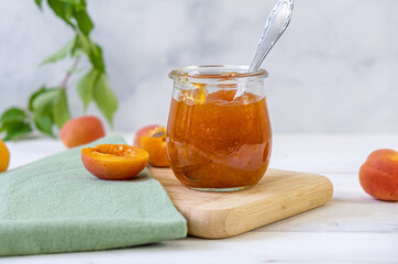 Homemade apricot jam in glass jar on kitchen white background. Summer harvest and canned food. 