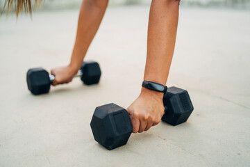 Woman doing push-ups with dumbbells and smart watch