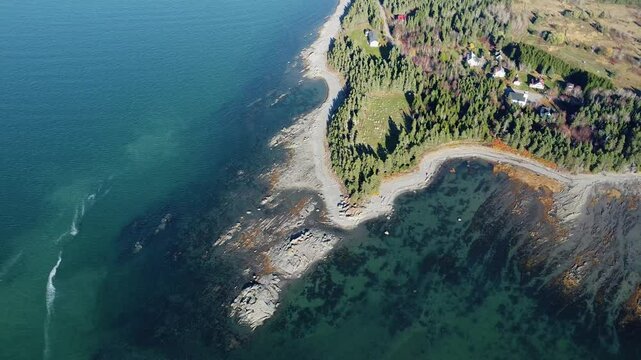 High‑altitude aerial view of the transparent waters of the St. Lawrence River exposing the rocky seabed along La Pointe‑Leggatt and Mitis Bay on the scenic Gasp&eacute; Peninsula in Quebec, Canada.