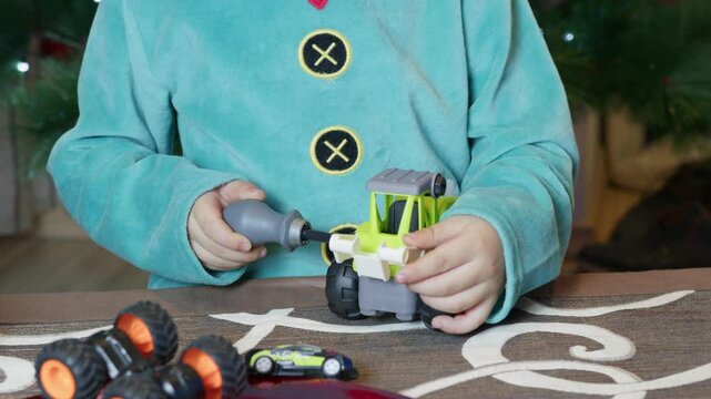 Cute boy elf assembling toys for kids in front of Christmas tree. High quality 4k footage