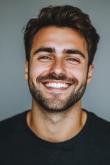 Obraz premium Young man with a beautiful smile on a grey background, ideal for dental ads.