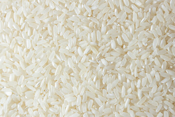 Dry Uncooked White Rice Background - Top View, Flat Lay. Scattered Raw Long Grain Rice. Asian Cuisine and Culture. Healthy Eating Ingredients. Diet Food