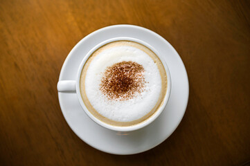 Ceramic cup of cappuccino on brown table