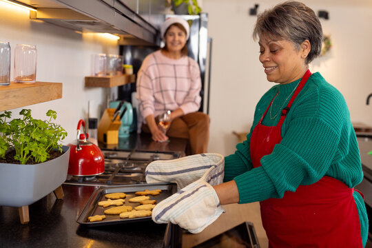 Baking Christmas cookies, senior female friends enjoying festive time in cozy kitchen, at home