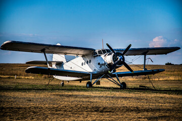 a propeller plane biplane stands in a field against the sky