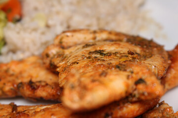 chicken with selective focus. meal details grilled chicken with rice in the background.
