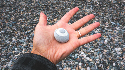 Woman hand holding a stone on a pebble beach feminine