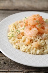 Delicious risotto with shrimps and cheese on wooden table, closeup