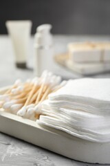 Clean cotton pads and swabs on grey table, closeup