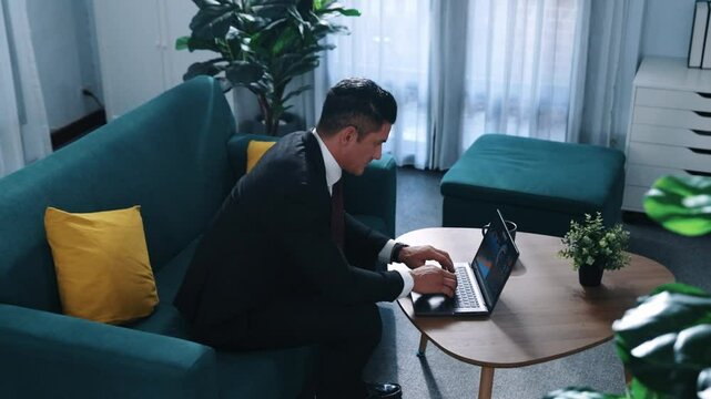 Stressful boss look at decrease sales from laptop and lies on sofa. Professional tired project manager working laptop while feeling stress. Skilled business man having headaches at work. Directorate.