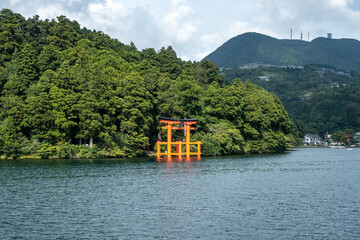 Scenic view of the hakone shrine's orange torii gate in lake ashi, with lush greenery and mount...