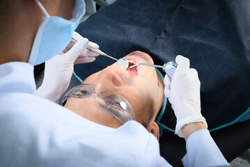 A dental professional focuses on the examination of a patient's oral health using specialized tools in a well-lit clinic, providing care and attention during the appointment.