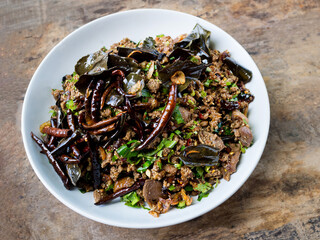 Spicy duck salad with vegetables and chillies on wood background, Thai style