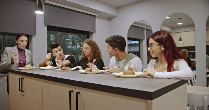 A professor and students share a meal in the school cafeteria between classes, enjoying food and conversation, fostering mentorship and strengthening bonds through informal interaction.