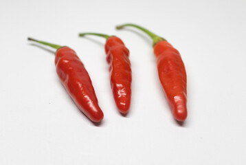 Set of three red chili peppers arranged against a white background.