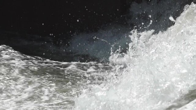 Slow motion closeup of a large wave of whitewater crashing in a concrete channel