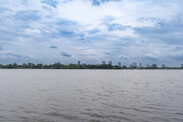 Calm river with a city skyline under a cloudy sky, creating a serene and peaceful scene