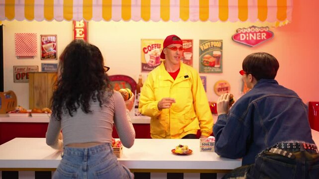 Multicultural customer dancing and holding junk food while waiter moving to freestyle music. Happy restaurant coworker standing behind bar while perform energetic movement and footstep. Regalement.