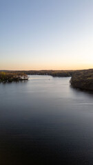 Tranquil sunset over a serene lake, capturing the peaceful reflections of fading sunlight on calm waters with silhouetted trees on the shoreline.