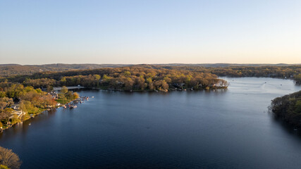 Tranquil sunset over a serene lake, capturing the peaceful reflections of fading sunlight on calm waters with silhouetted trees on the shoreline.