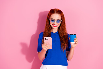 Photo of adorable lovely woman wear blue trendy clothes hold device drink tea read news isolated on pink color background