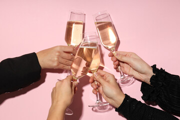 Glasses of champagne in hands on a pink background