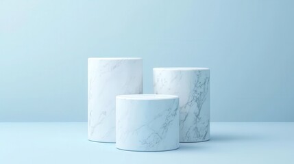 Elegant marble cylinders in varying sizes set against a soft blue background, creating a minimalist aesthetic.