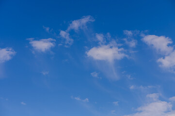 A serene expanse of blue sky adorned with soft, wispy clouds stretching across the horizon in midday light