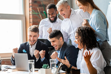 Happy Business People At Laptop Celebrating Success At Work Sitting In Modern Office. Successful Negotiations